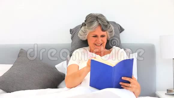 一个年轻的女人在床上看书视频的预览图