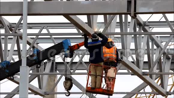 工人们在一个工业升降机的帮助下在一个高度焊接金属制品视频的预览图