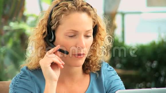 卷发女人在耳机上说话视频的预览图