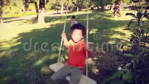 快乐的小男孩在秋千上视频的预览图