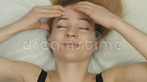 金发女人做自我按摩面部按摩躺在家里的床上视频的预览图