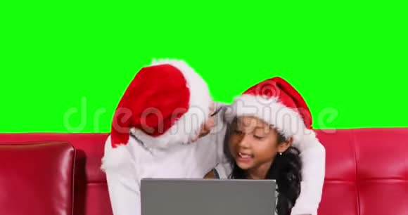 女孩和她妈妈在沙发上用笔记本电脑视频的预览图