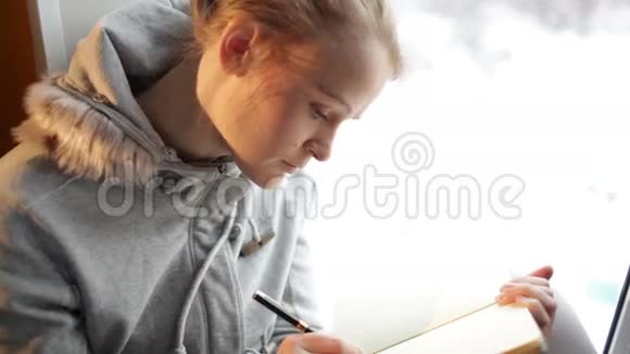 年轻漂亮的女孩在她的日记里写作和白日梦视频的预览图