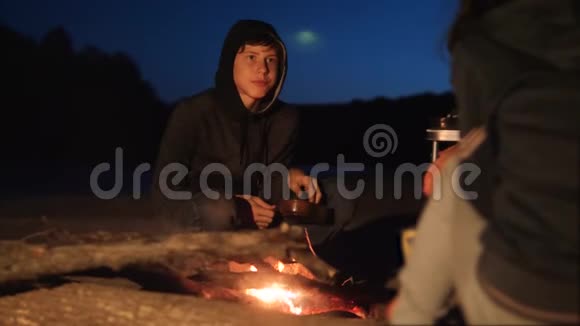 孩子们剪影孩子们坐在火边晚上在篝火旁吃爆米花旅行徒步旅行冒险露营视频的预览图