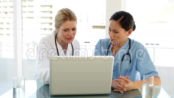 医生和护士在翻手提电脑上的档案视频的预览图