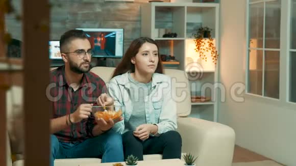 年轻夫妇坐在沙发上看电视视频的预览图