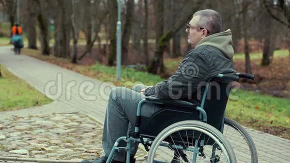 坐轮椅的残疾人在公园的小路上等候视频的预览图