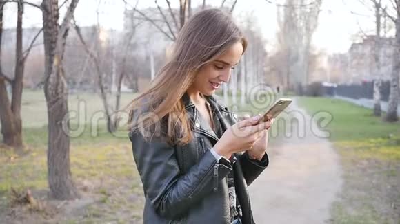 公园里漂亮的年轻女人用电话晚上穿过市中心一个年轻的女人走在视频的预览图