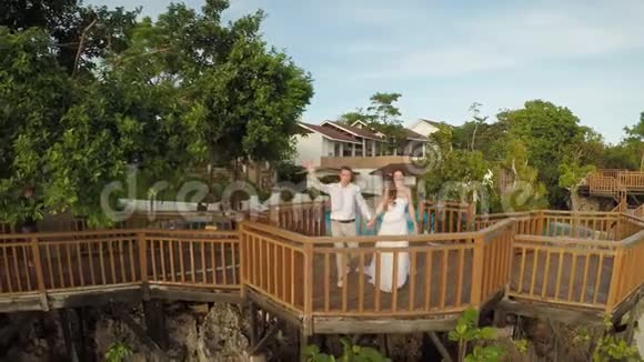 一个美丽的浅绿色海岸珊瑚礁和一对相爱的夫妇在阳台上的海滩美丽的大自然视频的预览图