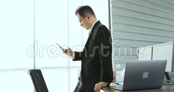 亚洲商人在办公室里用手机视频的预览图