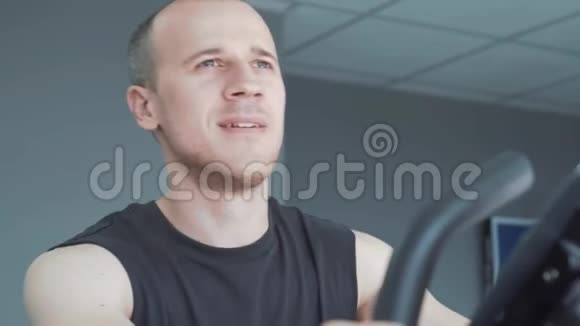 年轻有魅力的人骑着健身车在健身房里骑自行车视频的预览图