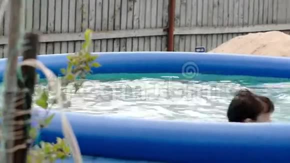男孩在院子里的充气游泳池里游泳视频的预览图
