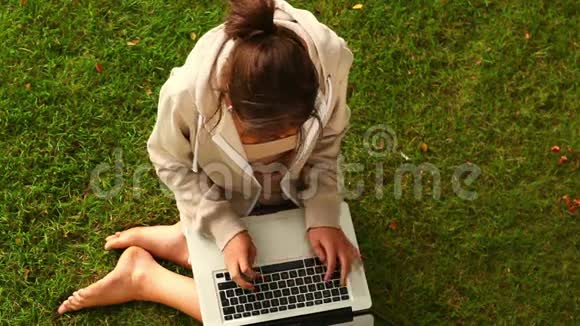 坐在草坪上拿着笔记本电脑工作的学生视频的预览图