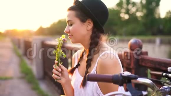 夕阳西下一个年轻漂亮的女人坐在自行车上开着花视频的预览图