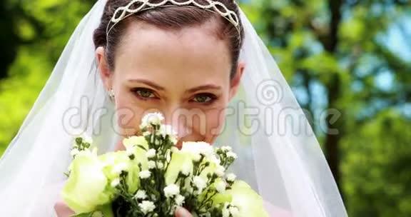 漂亮的新娘对着镜头微笑闻着她的花束视频的预览图