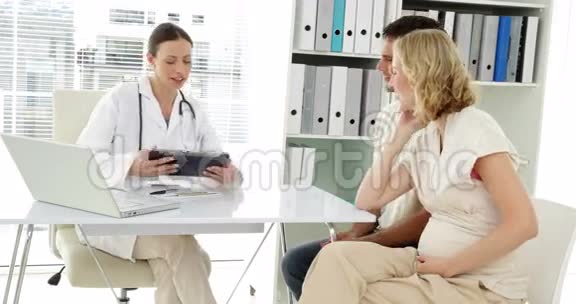 医生与准父母交谈给他们看平板电脑视频的预览图