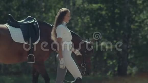 穿着白色西装的骑手牵着马的缰绳女骑手视频的预览图