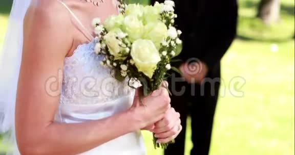 漂亮的新娘对着镜头微笑新郎站在后台视频的预览图