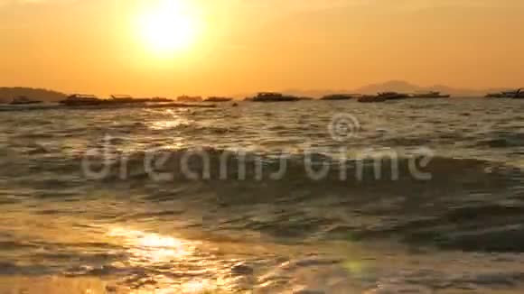 在群山的映衬下海滩上有一片红色的夕阳海浪拍打着岸边视频的预览图