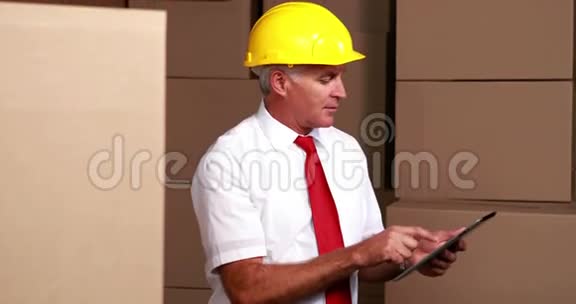 仓库经理坐着使用他的平板电脑视频的预览图