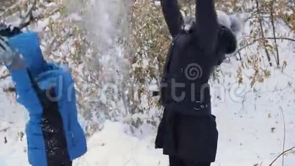 女孩和孩子把雪洒在自己身上在冬天的公园里享受它视频的预览图