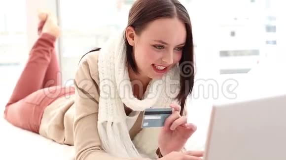 漂亮的黑发女人在床上用笔记本电脑在网上购物视频的预览图