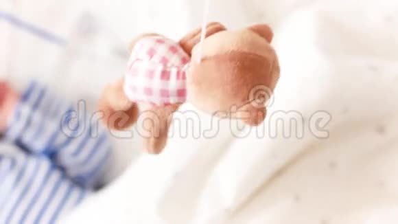 顶部的照片可爱的婴儿与另一个躺在婴儿床和看旋转的小熊玩具视频的预览图