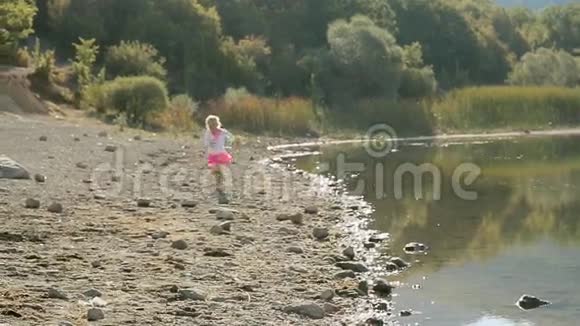 小女孩慢慢地沿着湖岸奔跑视频的预览图