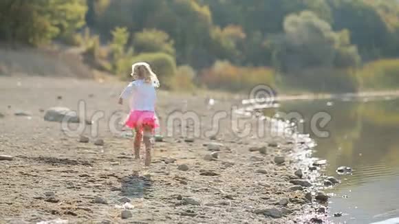 小女孩慢慢地沿着湖岸奔跑视频的预览图
