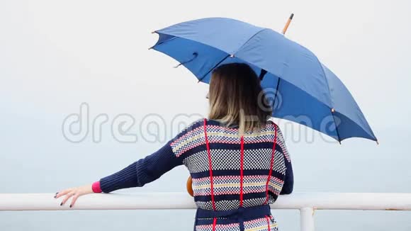 后面的女人带着雨伞在码头上放松海洋视频的预览图