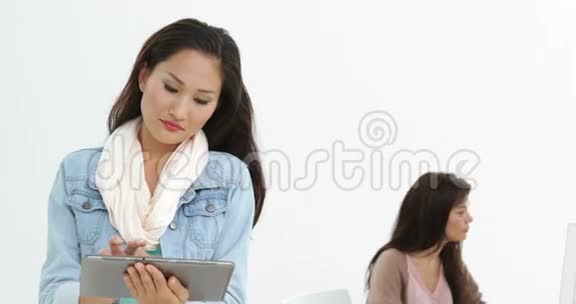 有创意的女商人用她的平板电脑和她身后的同事视频的预览图