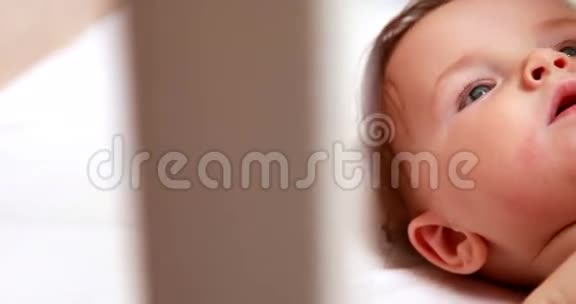 婴儿在尿布里玩手机在婴儿床上视频的预览图