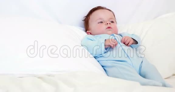 穿着蓝色婴儿裤的小男孩躺在枕头上视频的预览图