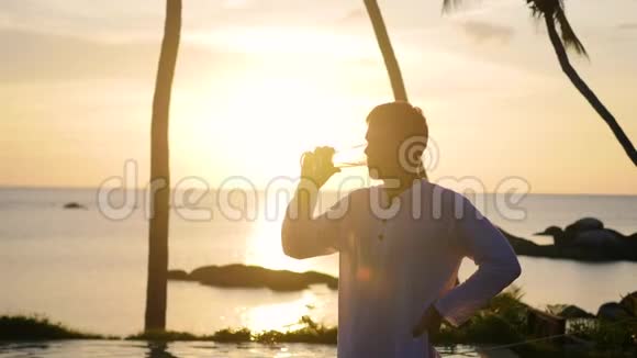 坐在沙滩上喝啤酒的人日落时分视频的预览图