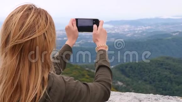 山顶的年轻女子慢镜头自拍年轻的徒步旅行者女人拍照视频的预览图