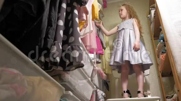 漂亮的小女孩在家庭衣柜里选择连衣裙美丽与时尚视频的预览图
