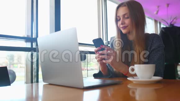 女人在咖啡馆里用智能手机打短信一位年轻女士坐在桌旁用手机端着咖啡视频的预览图