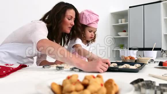 母亲和女儿数着他们烤的饼干的数量视频的预览图