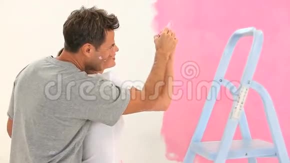 可爱的一对夫妇画了一堵粉红色的墙视频的预览图