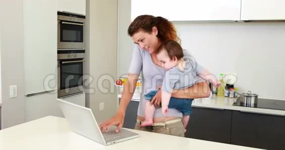 妈妈抱着她快乐的小男孩用手提电脑打电话视频的预览图