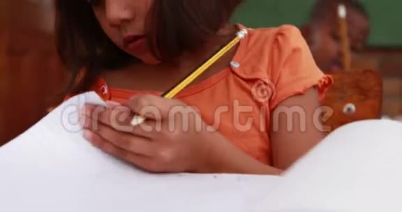 小女孩在书桌旁的教室里翻书视频的预览图