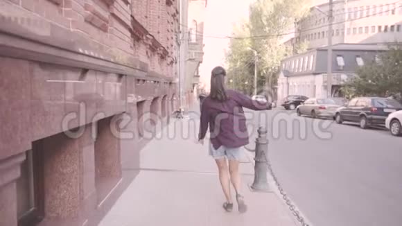 美丽的年轻开朗的女孩正在城里散步挥动双手奔跑视频的预览图