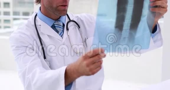 英俊的医生在检查X光和相机微笑视频的预览图