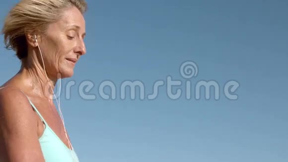 在阳光明媚的日子里听音乐慢跑的老妇人视频的预览图