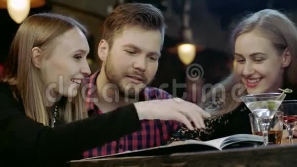 快乐的年轻人坐在酒吧里看菜单卡视频的预览图