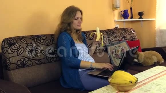 怀孕女孩用电脑吃香蕉爱抚肚子视频的预览图