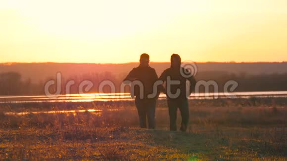 两个人站在夕阳上的剪影背包表达了能量和幸福旅行概念视频的预览图