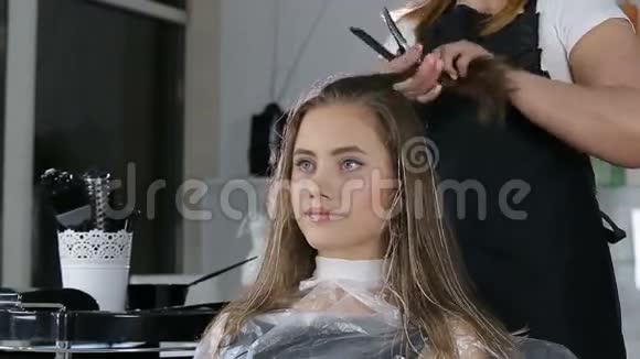 专业的理发师为少女准备发型用理发器修头发视频的预览图