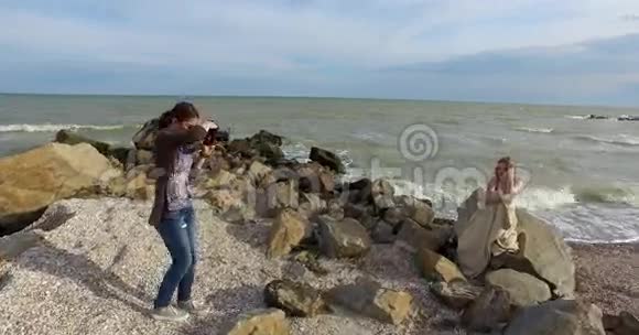 女孩模特坐在岩石上为摄影师摆姿势视频的预览图