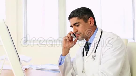 医生在办公桌前工作在打电话视频的预览图